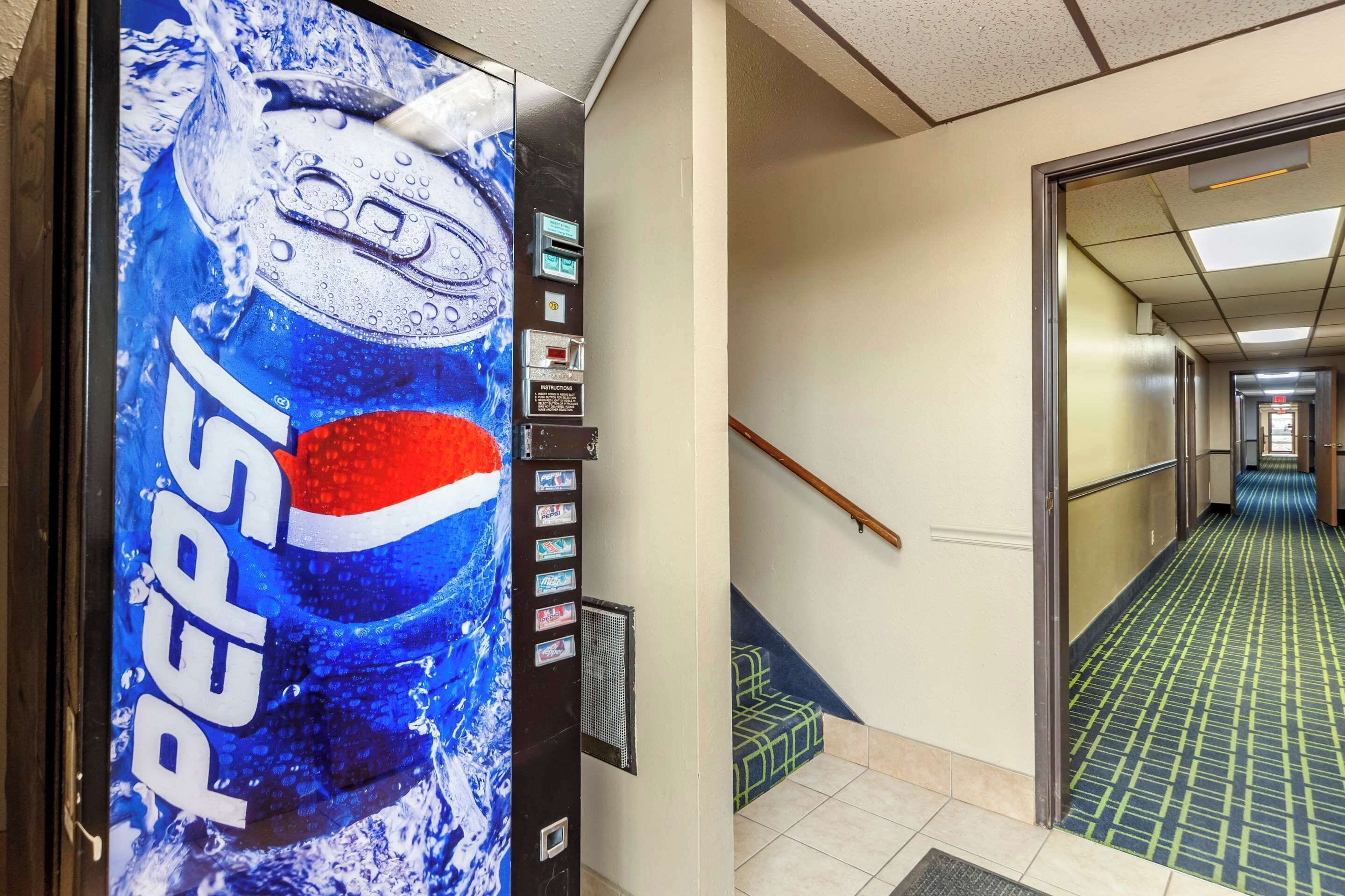 A hallway with a Pepsi vending machine, a staircase, and a patterned floor.