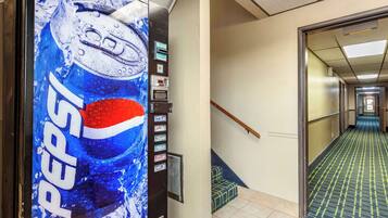 A hallway with a Pepsi vending machine, a staircase, and a patterned floor.