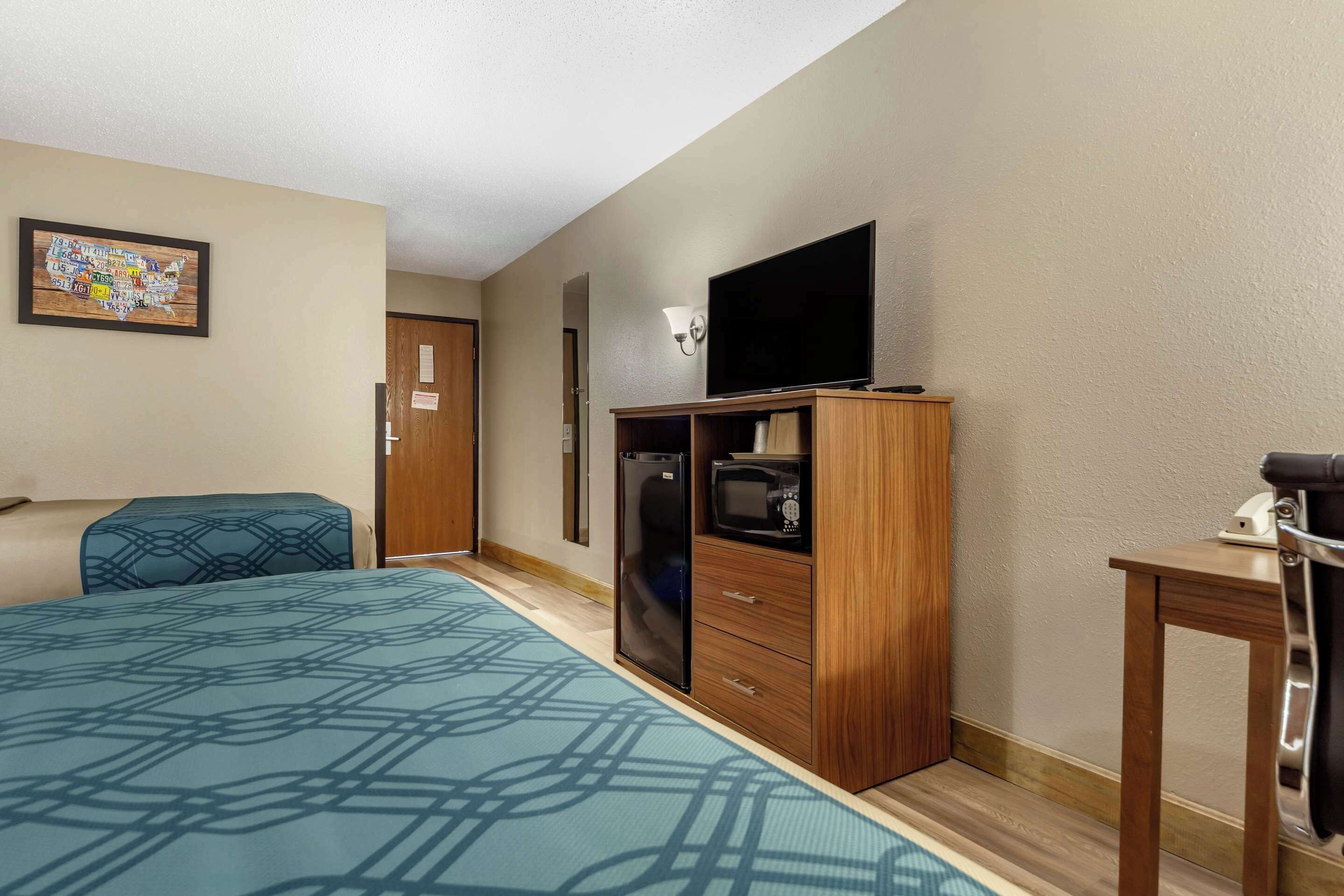 A hotel room with a bed, a TV, a microwave, and a desk.