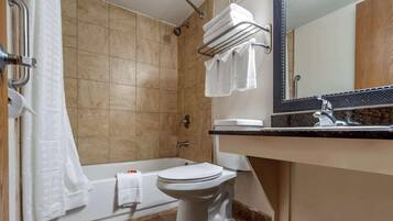 A modern bathroom with a bathtub, toilet, and a large mirror.