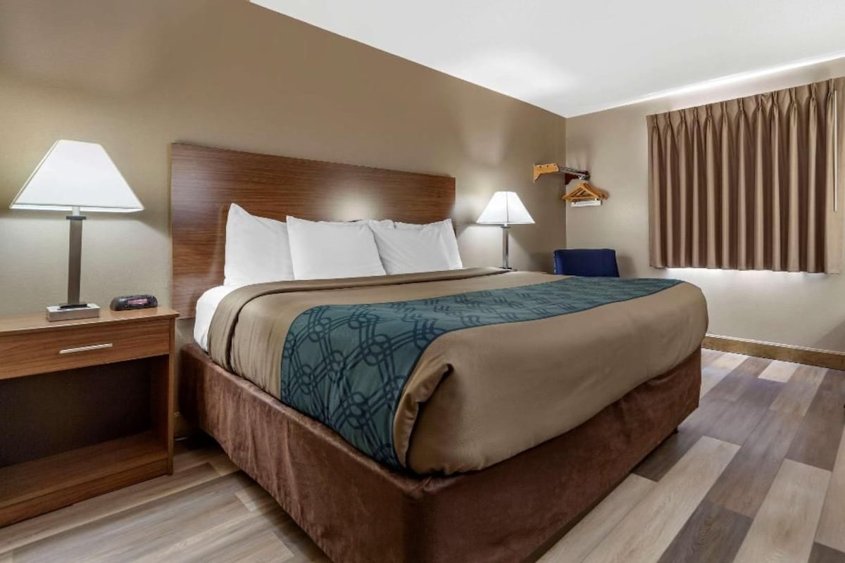 A hotel room with a large bed, two bedside tables, a nightstand, a desk, and a chair.
