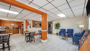 A hotel lobby with a reception desk, a coffee station, seating areas, and a small plant. - Econo Lodge Hays I-70 (Hays)