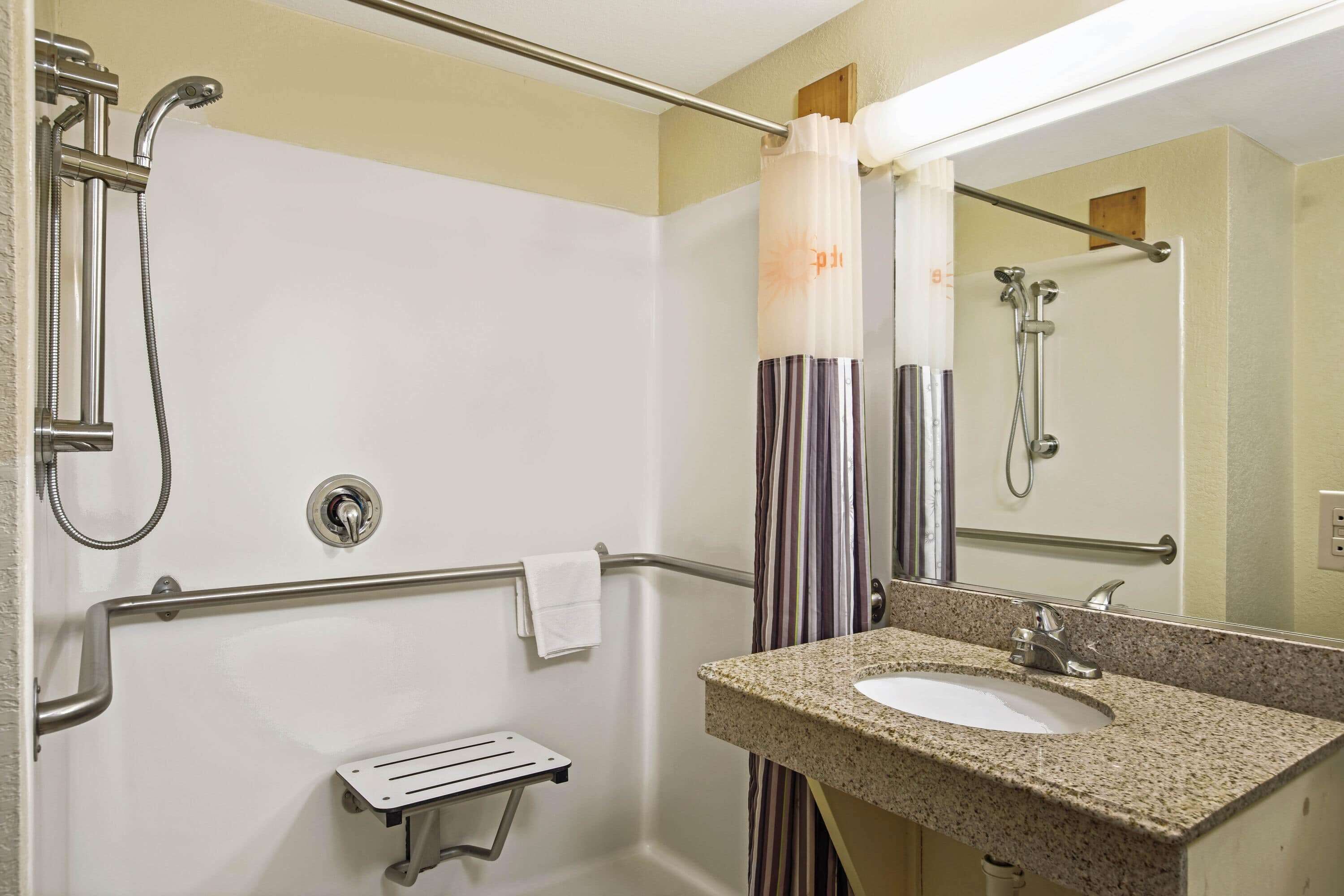 A bathroom with a shower, a sink, a towel rack, and a mirror.