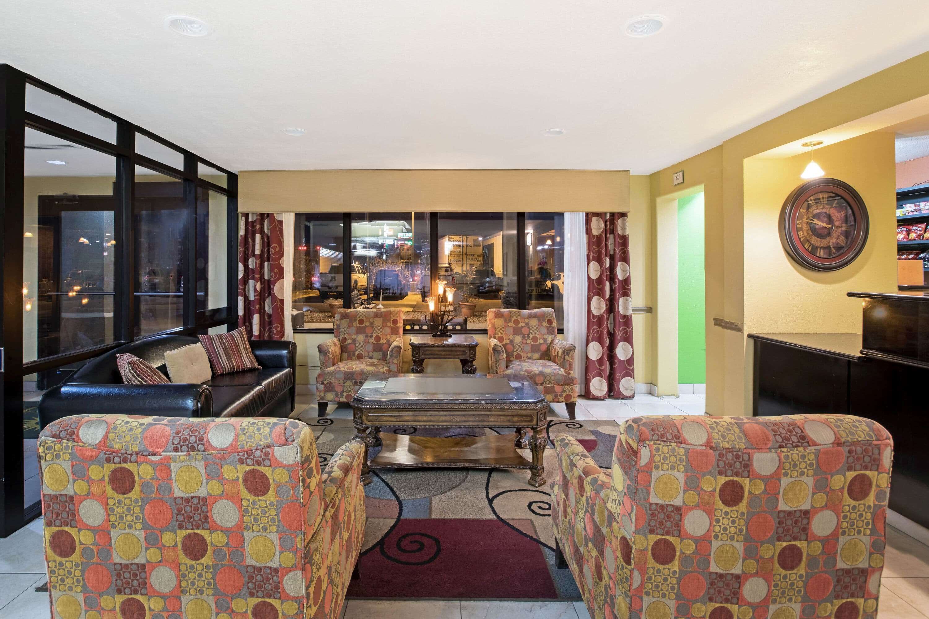 Un salon comprenant un canapé, des fauteuils, une table basse et un tapis à motifs.