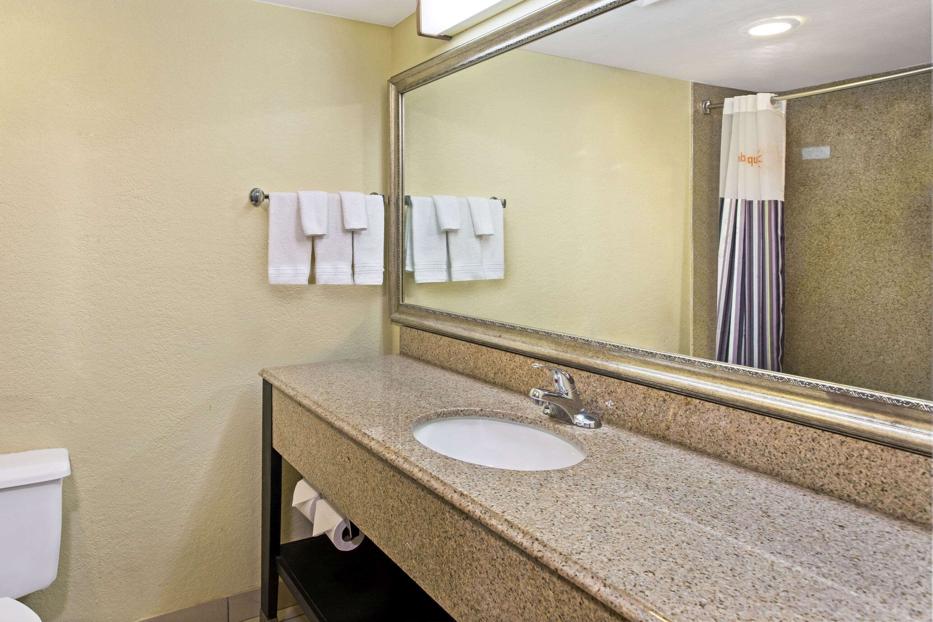 Ein Badezimmer mit Waschbecken, Spiegel und Handtüchern an der Wand.