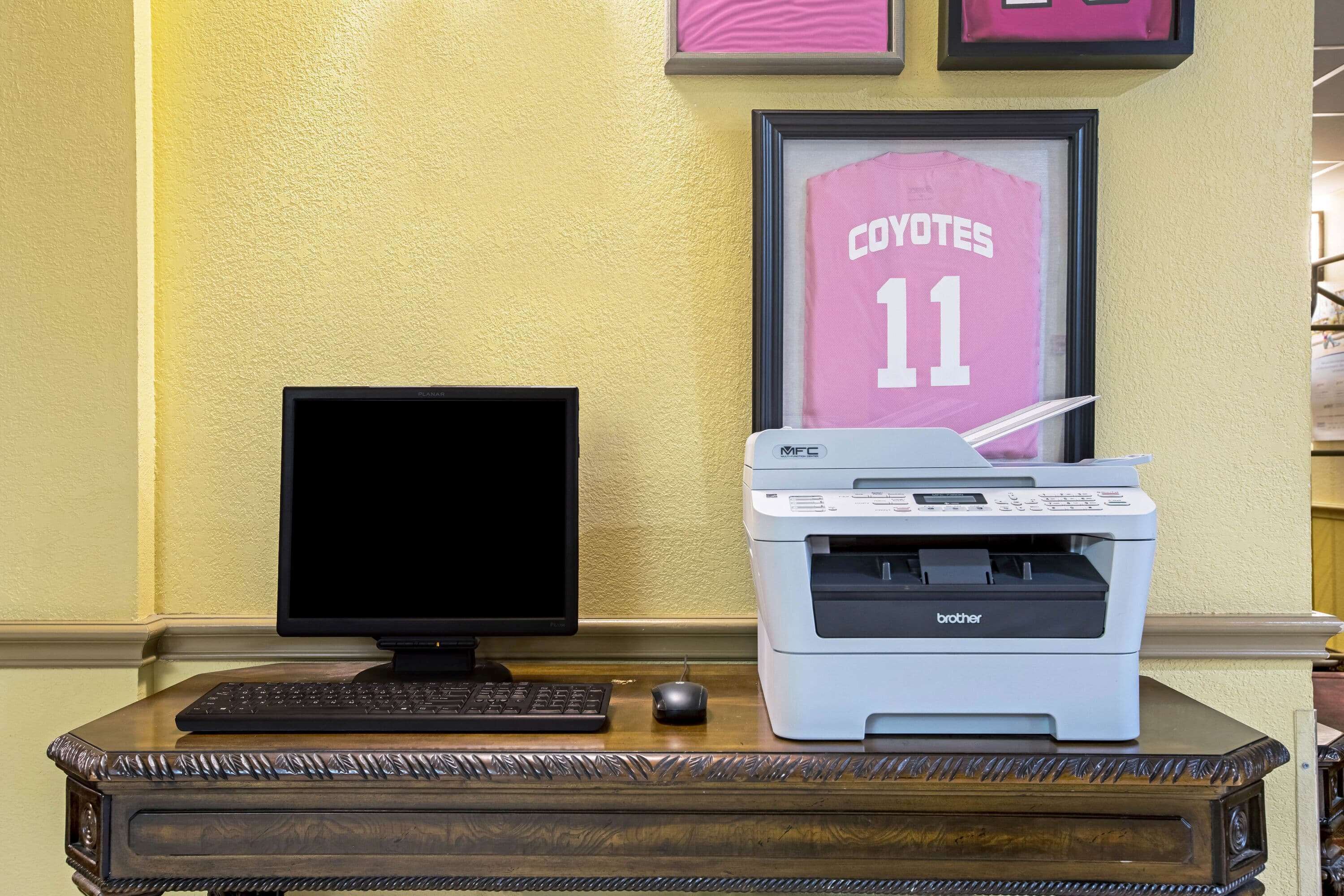 A desk with a computer monitor, keyboard, mouse, and a Brother printer.