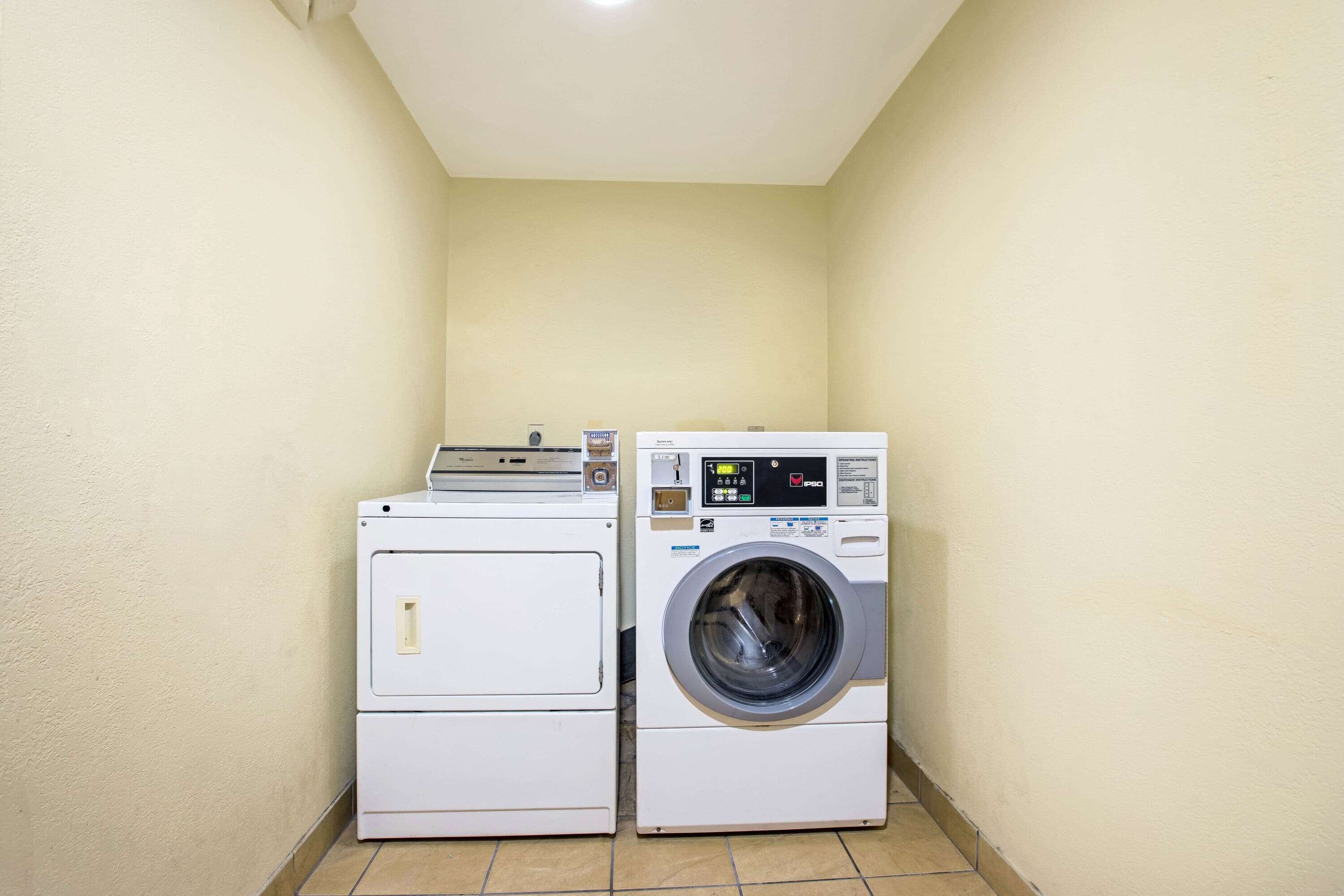A laundry room with a front-loading washer and dryer stacked against the wall.