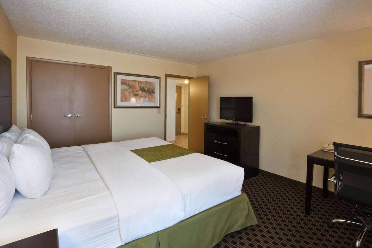 A hotel room with a bed, a television, a desk, and a wardrobe.