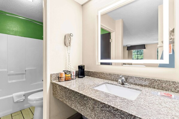 A bathroom with a white sink, a mirror, a telephone, and toiletries.