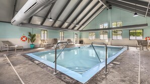 An indoor swimming pool with clear water, surrounded by lounge chairs and a potted plant. - Best Western Eagles Inn (Morehead)