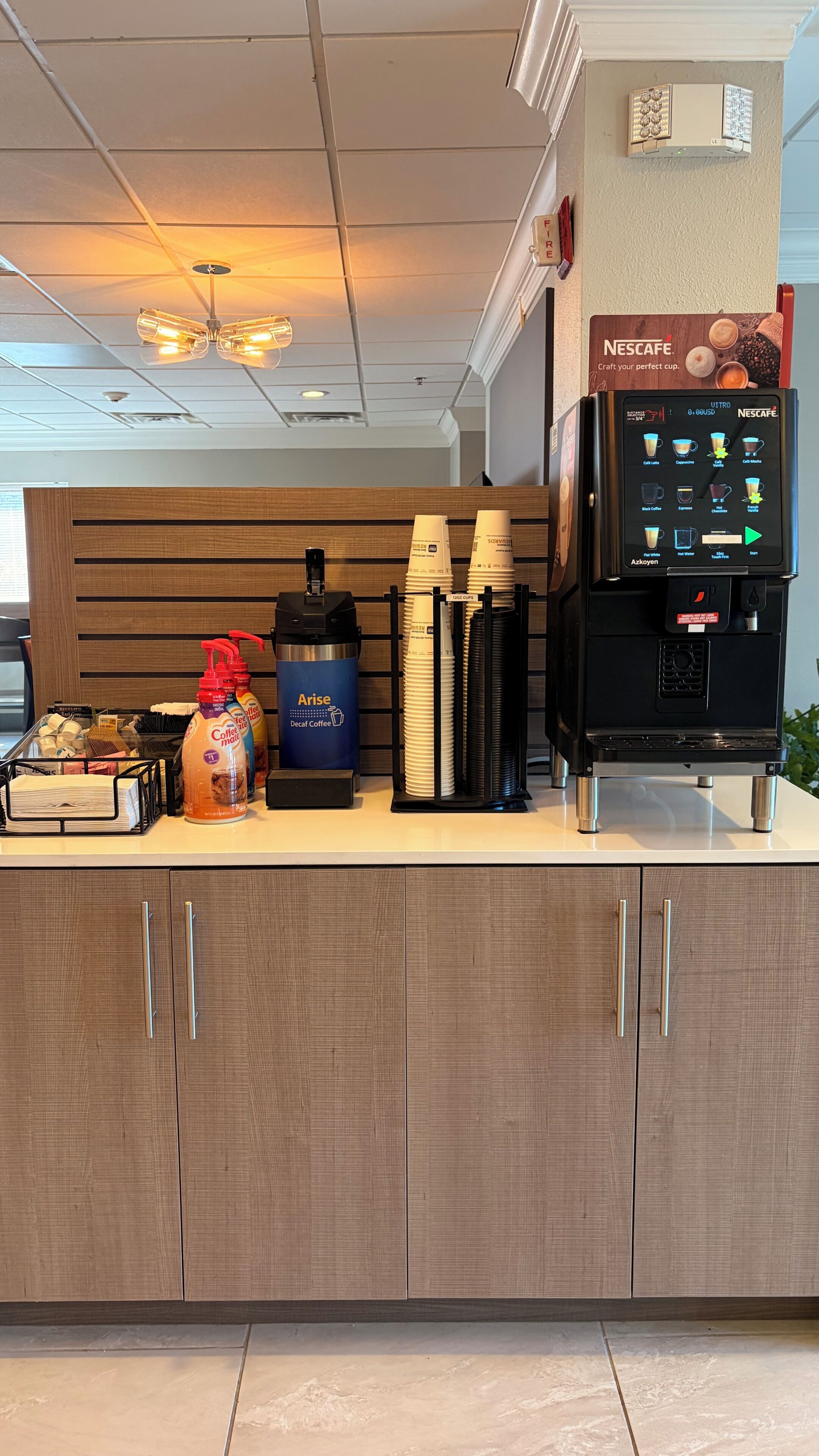 Un angolo caffè con una macchina Nescafe, bicchieri usa e getta e una macchina per il caffè.