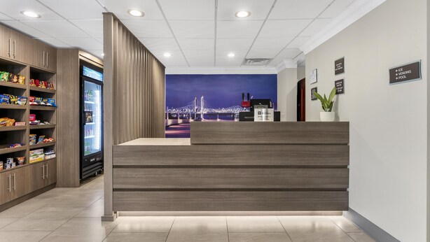 A reception area with a modern design, including a reception desk, a vending machine, and a wall-mounted sign indicating amenities like ice, vending, and pool. - Best Western Eagles Inn (Morehead)