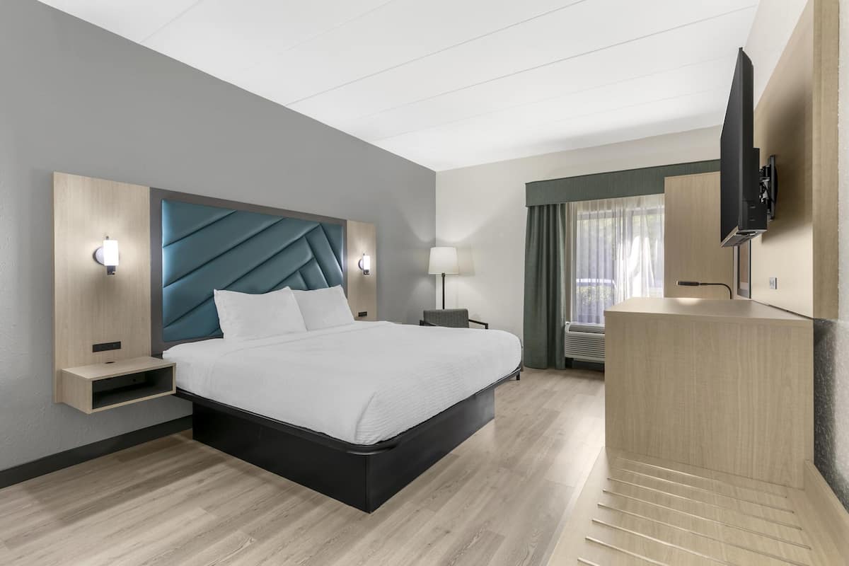 A modern hotel room with a large bed, a flat-screen TV, a desk, and a built-in wardrobe.