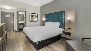 A modern hotel room with a bed, bedside tables, a desk, a mirror, and a wall-mounted light fixture. - Best Western Eagles Inn (Morehead)