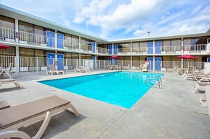Um hotel com piscina, várias varandas e áreas de estar ao ar livre.