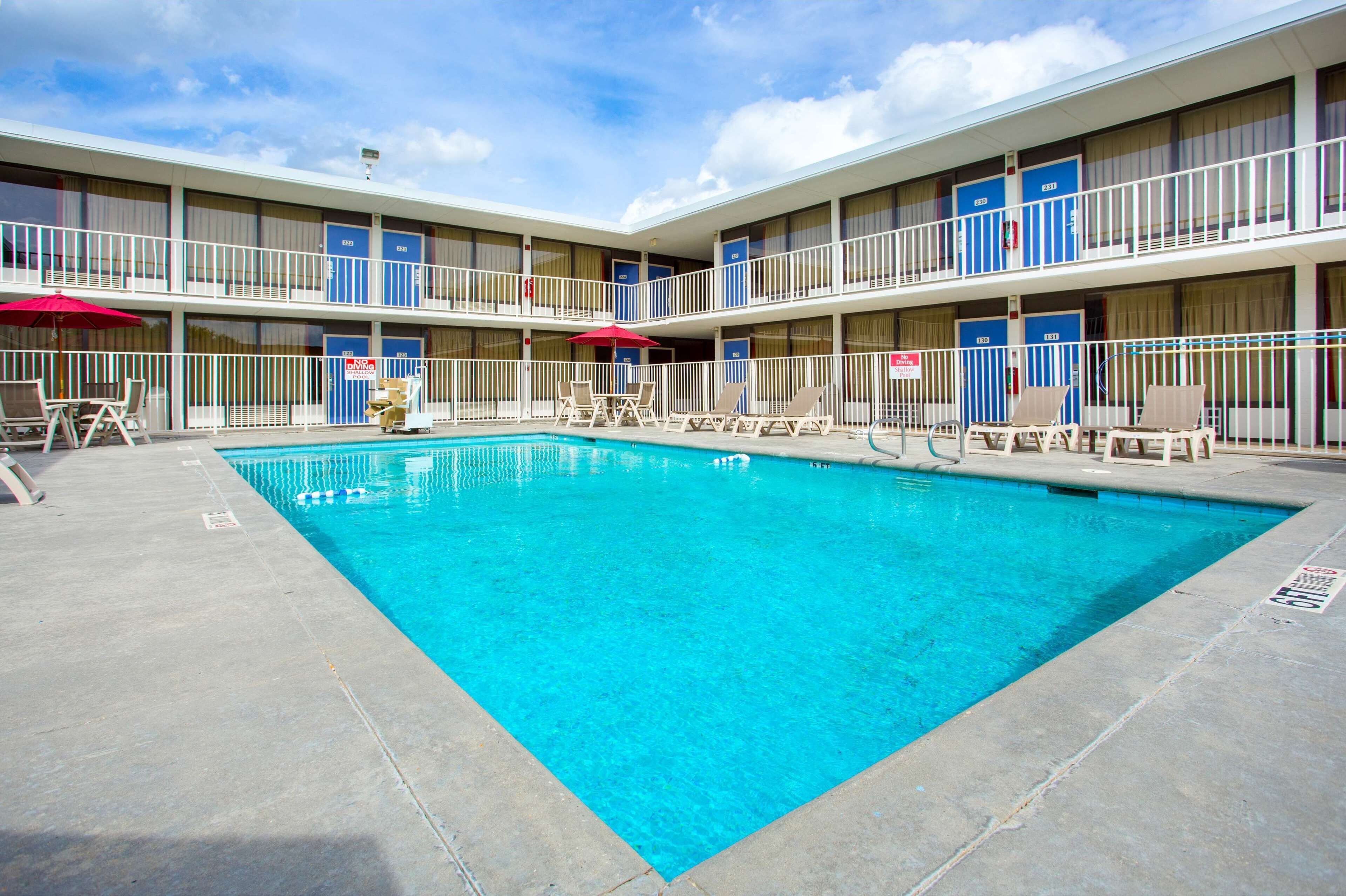 Ein Motel mit Schwimmbad, mehreren Balkonen und Liegestühlen.
