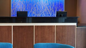 A reception desk with a blue abstract wall and two black speakers. - Fairfield Inn By Marriott Port Huron (Port Huron)