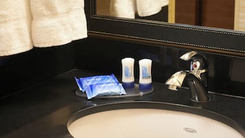 Un lavabo de salle de bain avec des articles de toilette, un miroir et une serviette.