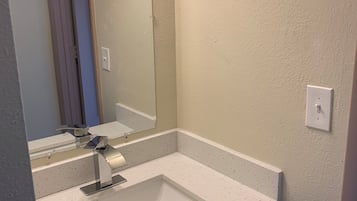 Ein Badezimmer mit weißem Waschbecken, einem Spiegel und einem Lichtschalter an der Wand.