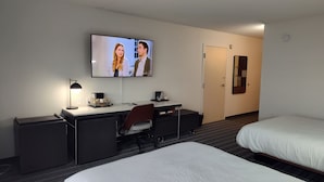 Una habitación de hotel con una cama, un escritorio con una silla, un televisor y una puerta.