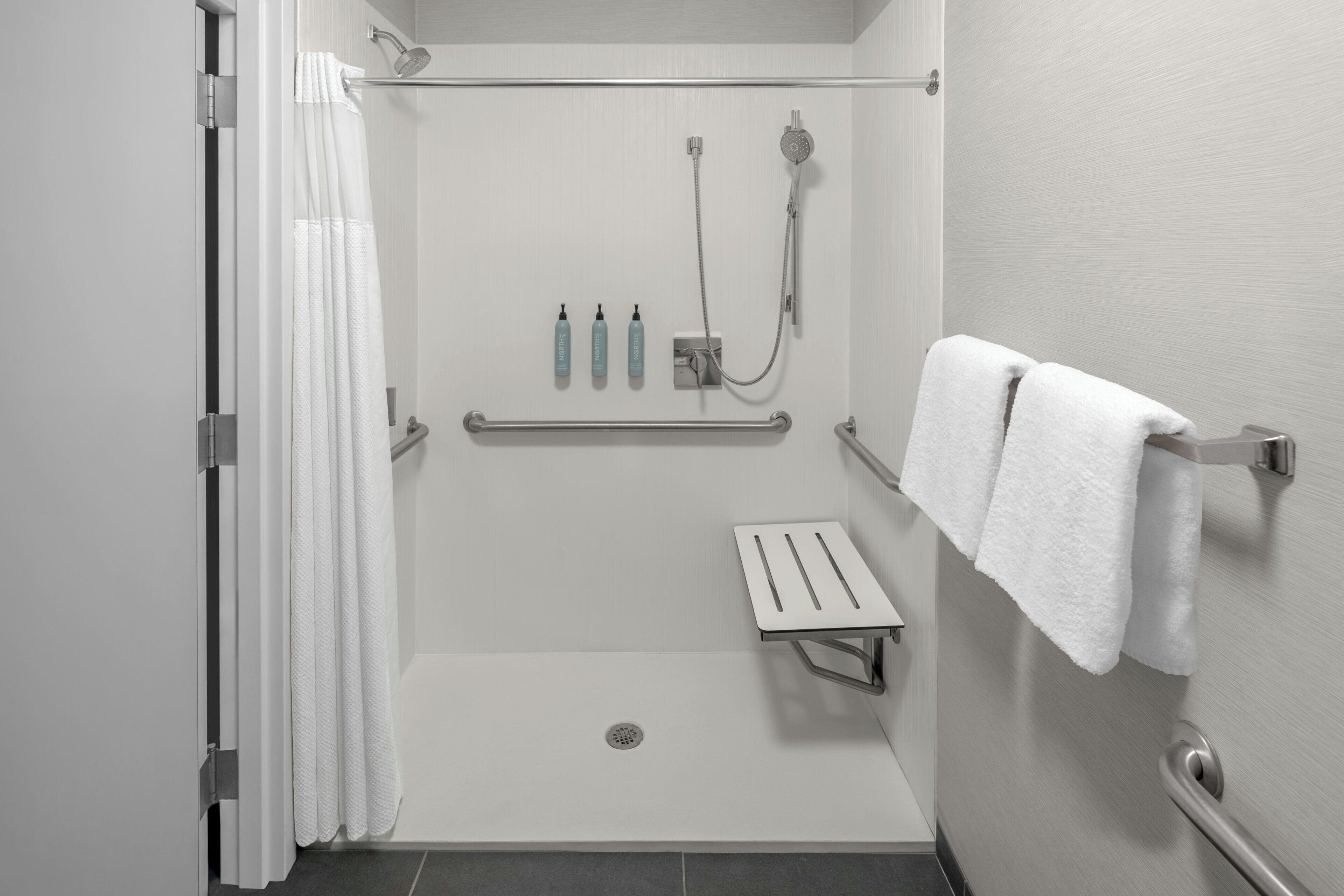 A walk-in shower with a grab bar, a towel rack, and a showerhead.