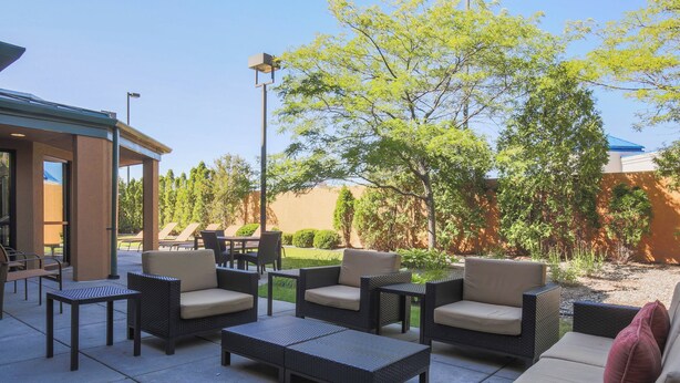 Un patio al aire libre con muebles de mimbre y una zona de estar cubierta.