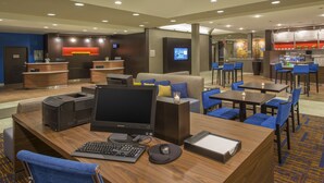 Un vestíbulo de hotel con mostrador de recepción, zona de estar y un pequeño bar.