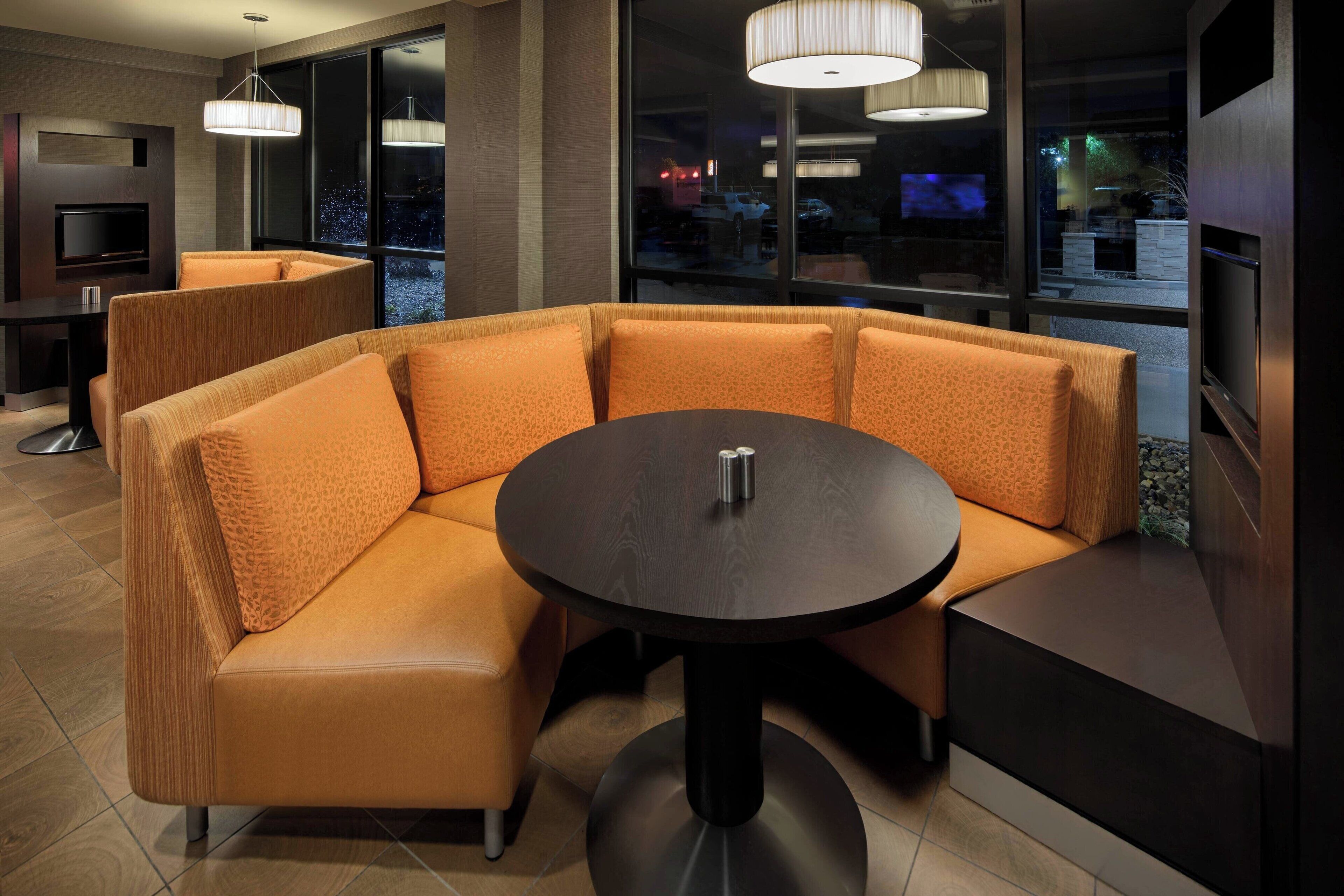 Un espace de détente moderne avec un canapé incurvé, une table ronde et un téléviseur.