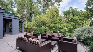 Un patio al aire libre con mobiliario de mimbre y una zona de estar cubierta.