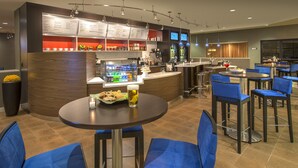 Un área de bar moderna con una pizarra de menú, asientos y un dispensador de bebidas.