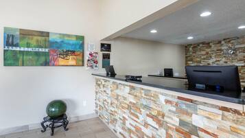 A reception desk with a stone wall, a clock, and a green spherical object on a stand.