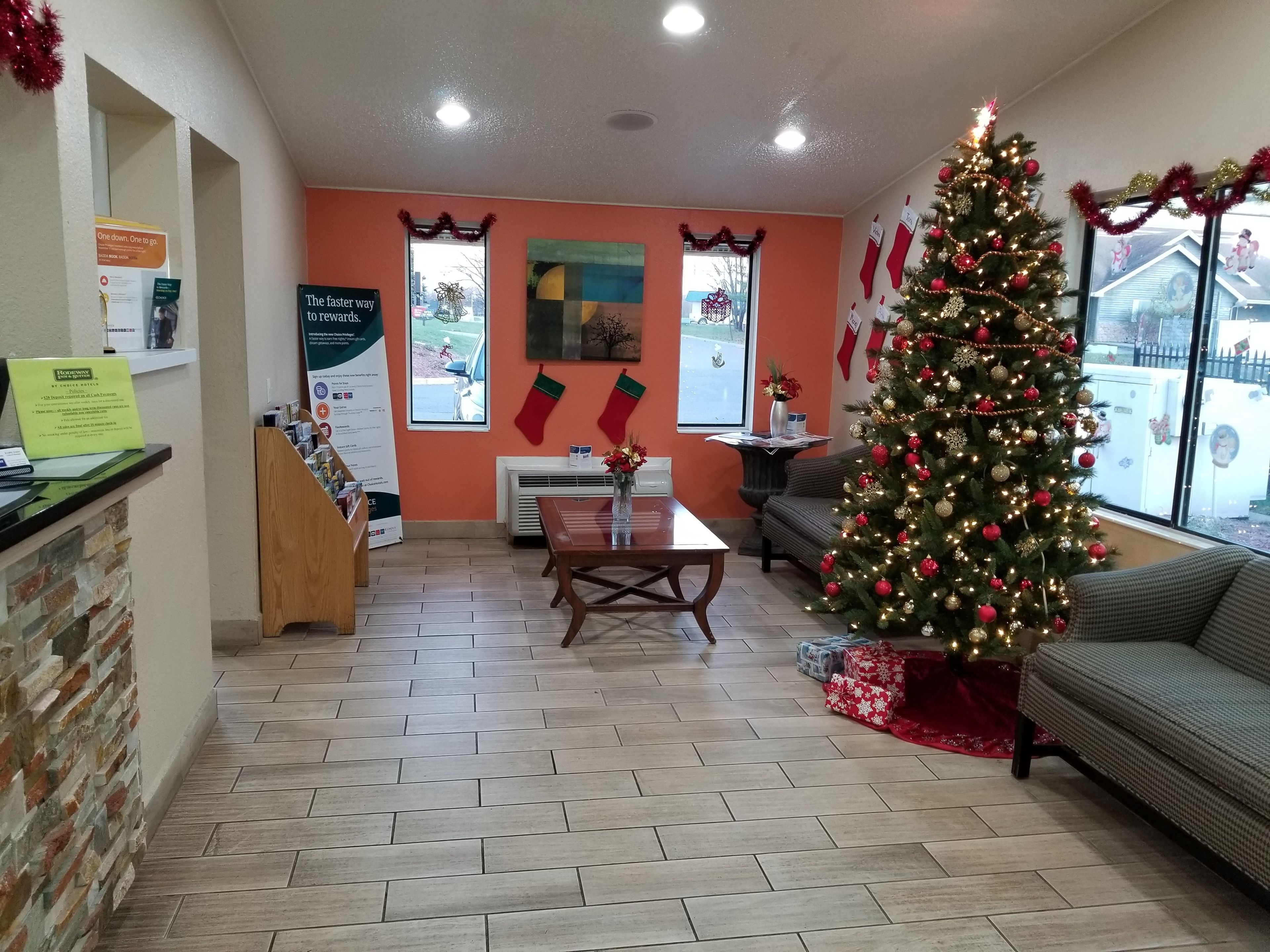 A warmly decorated reception area with a Christmas tree, a fireplace, and a seating area.