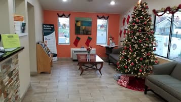 A warmly decorated reception area with a Christmas tree, a fireplace, and a seating area.