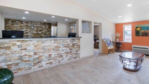 Una zona de recepción con pared de piedra, mostrador de recepción, una mesa redonda y un expositor.