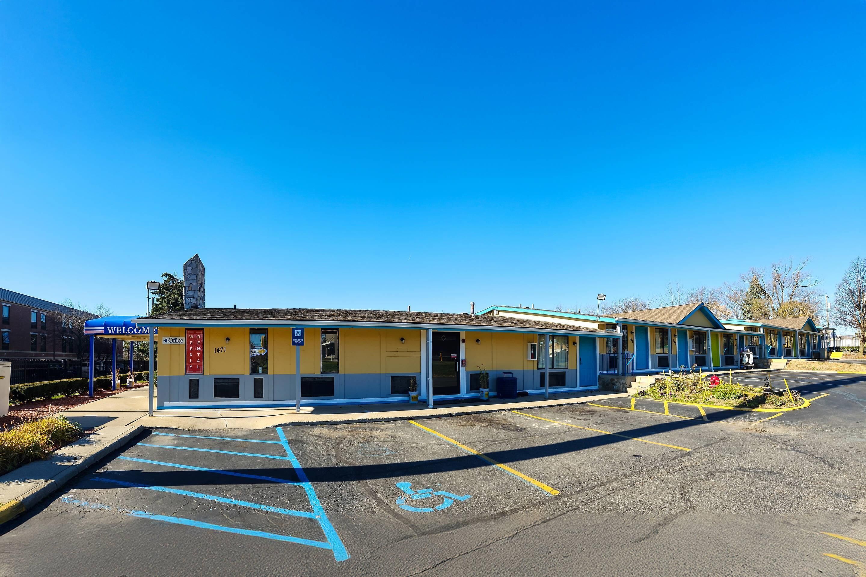 Un motel con estacionamiento, espacios accesibles para discapacitados y un letrero que indica la ubicación de la administración.
