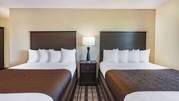 A hotel room with two beds, a nightstand with a lamp, and a patterned carpet.