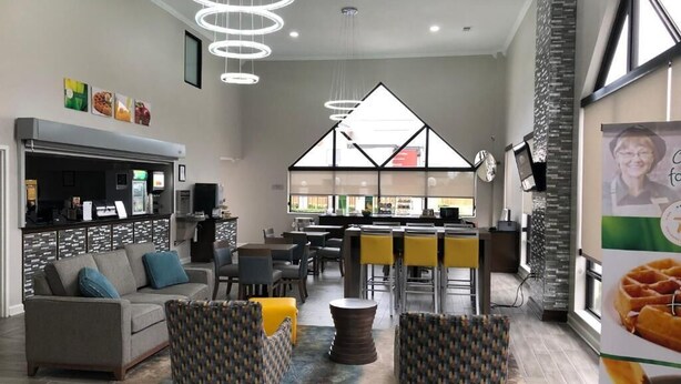Un moderno vestíbulo de hotel con zona de estar, un bar y un amplio ventanal.