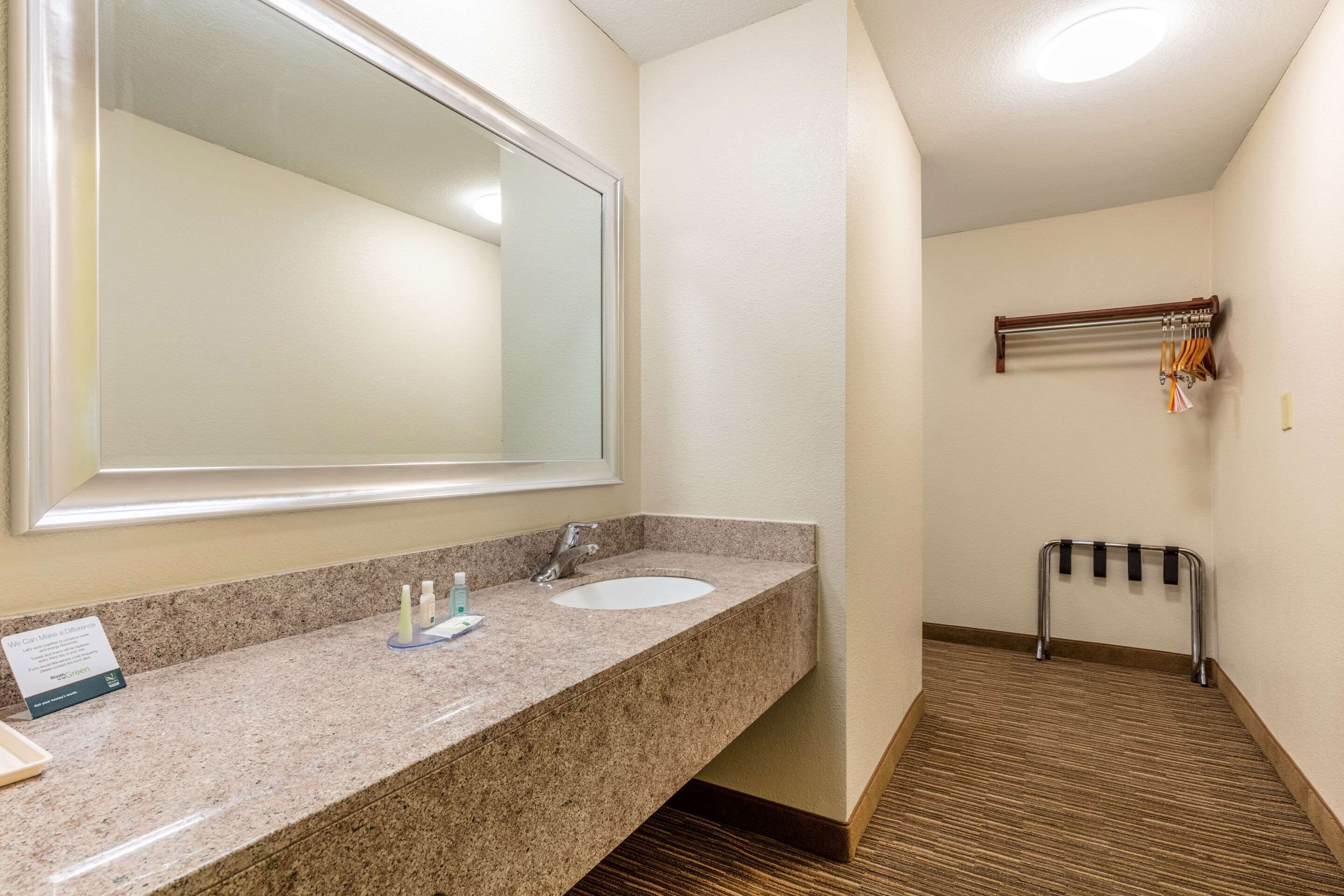 A bathroom with a granite countertop, a sink, a mirror, and a towel rack.