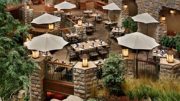 Un espace patio intérieur avec des murs en pierre, plusieurs tables, des chaises et des parasols.