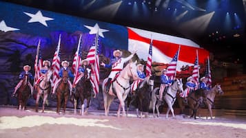 Un escenario con artistas a caballo, cada uno sosteniendo una bandera estadounidense.