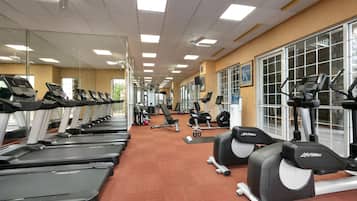 Un gimnasio con cintas de correr, elípticas y equipo de pesas.