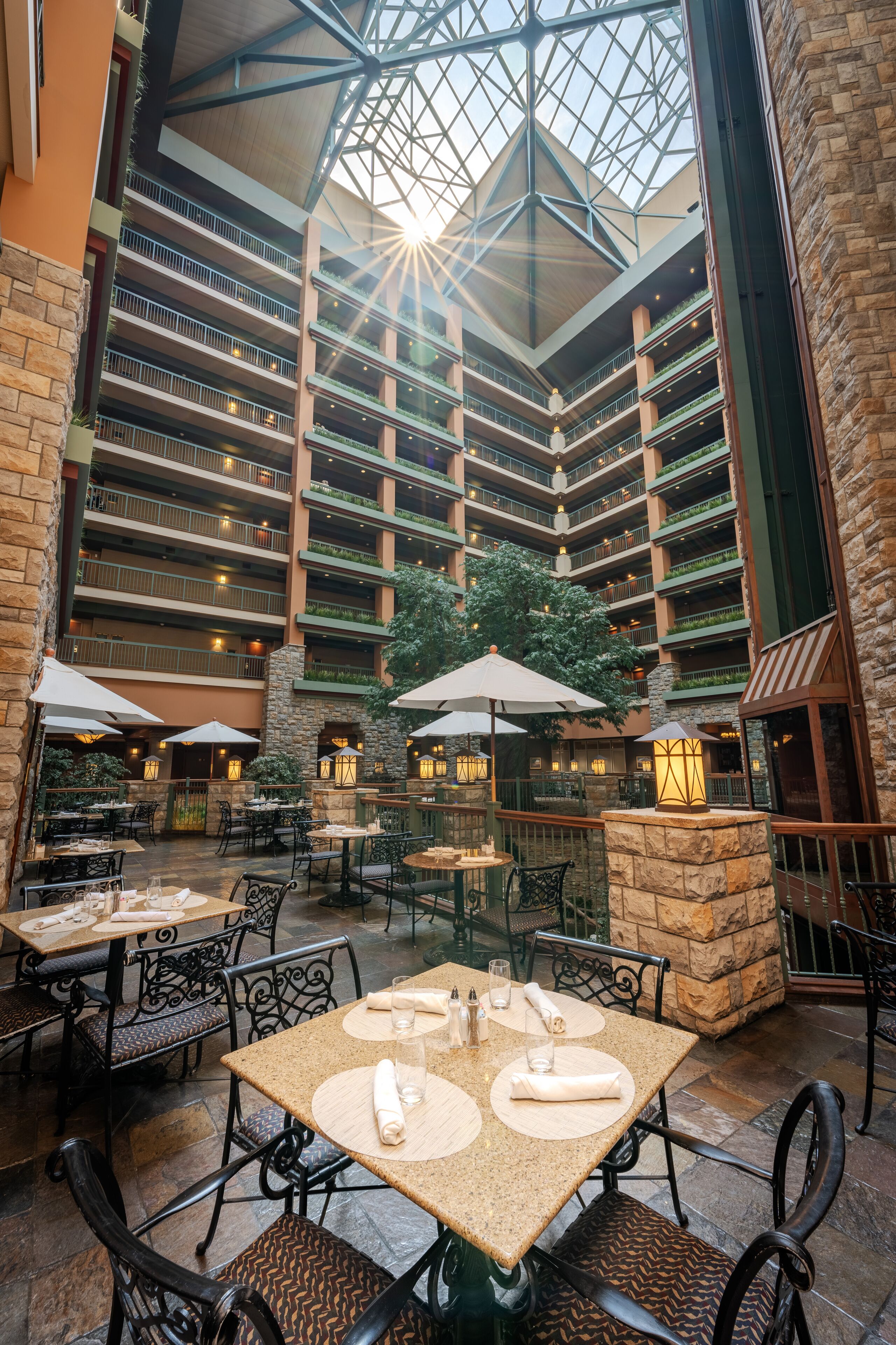 A multi-level atrium with outdoor seating, stone pillars, and a central glass ceiling.