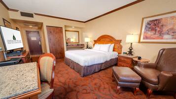 A hotel room with a bed, a desk, a chair, a sofa, and a carpeted floor.
