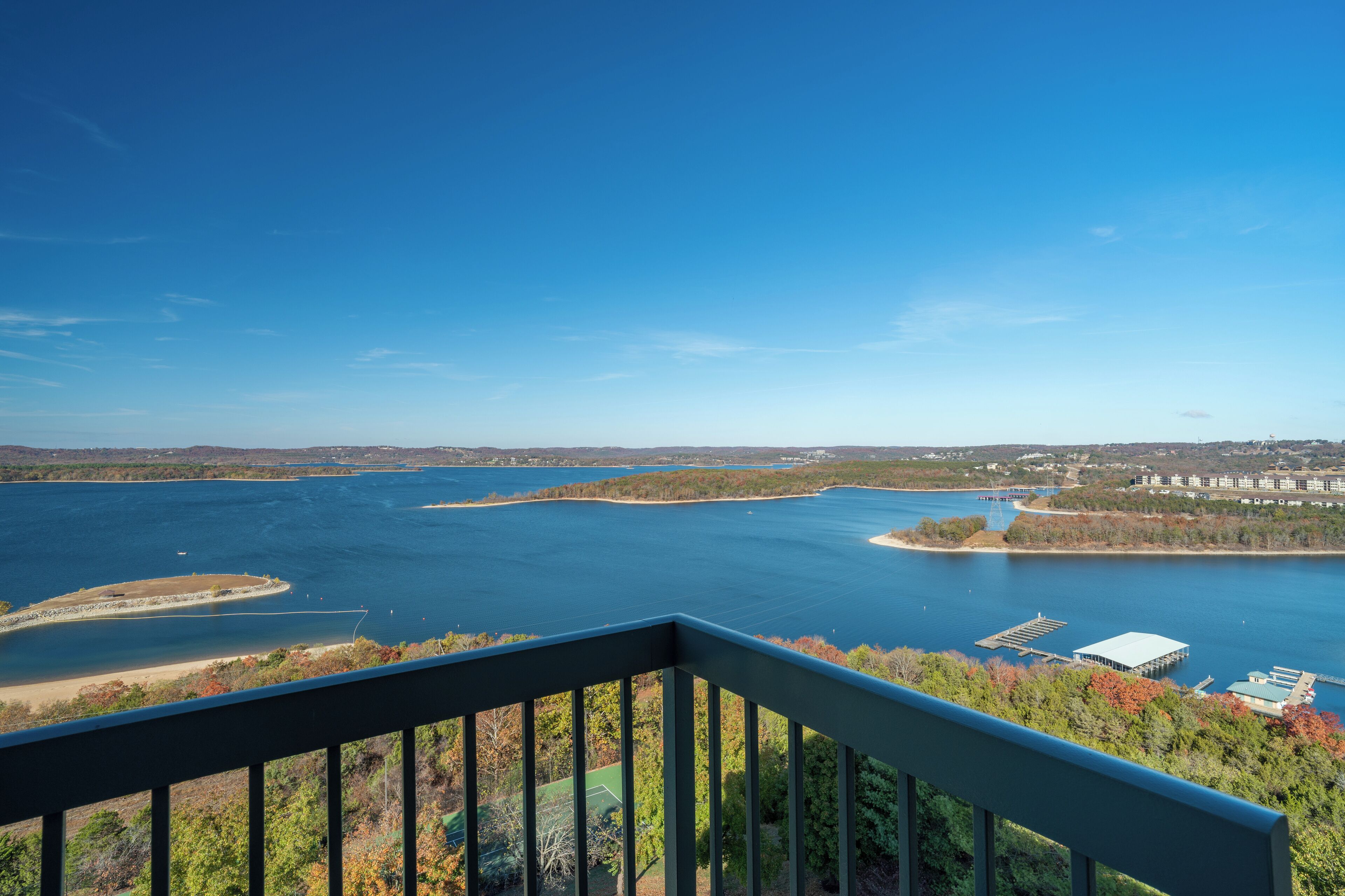 A panoramic view of a lake with a dock and buildings in the distance.