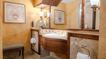 A bathroom with a wooden vanity, a large mirror, and a bench.