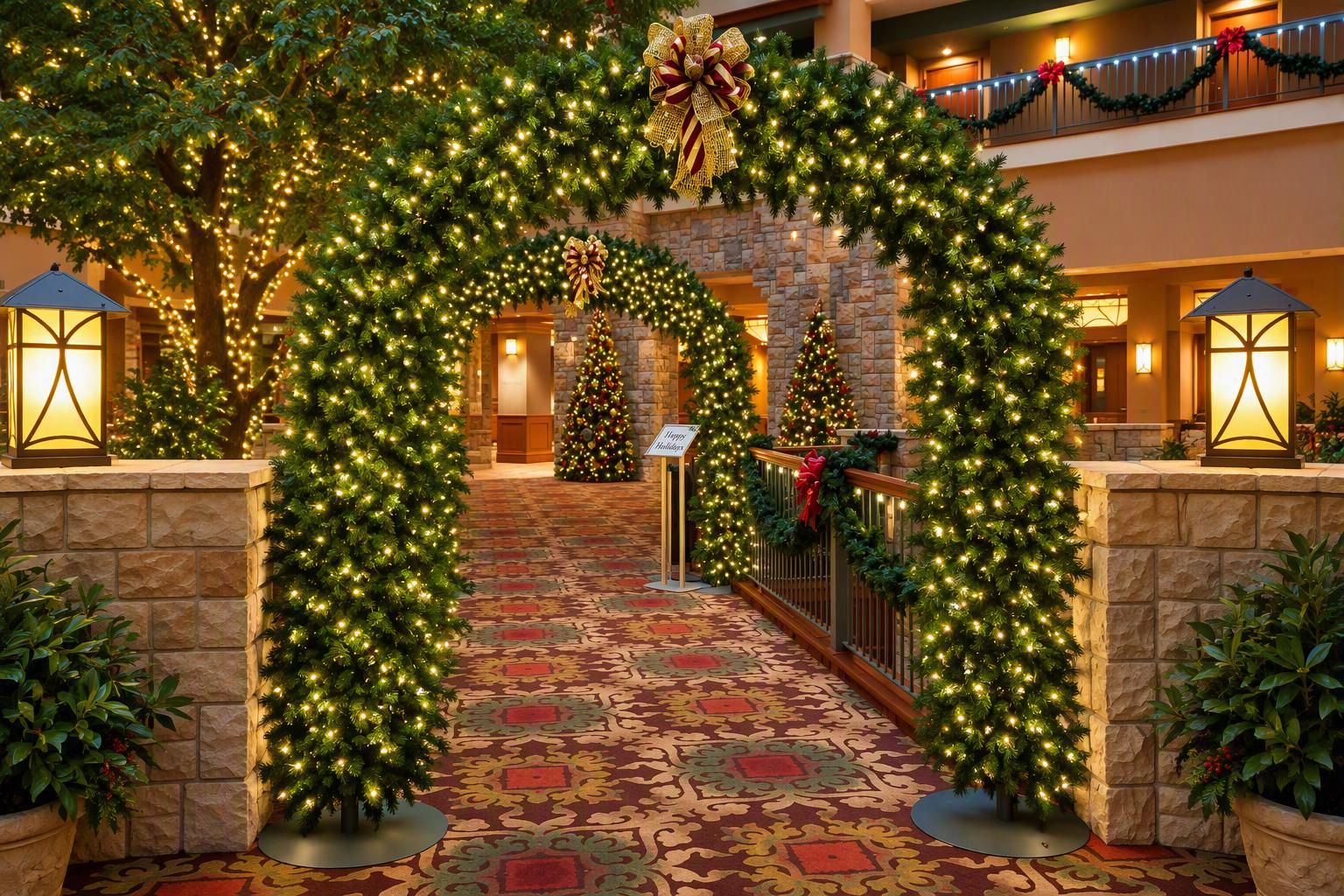 A hotel lobby decorated with Christmas trees and lights, a stone wall, and a carpeted floor.