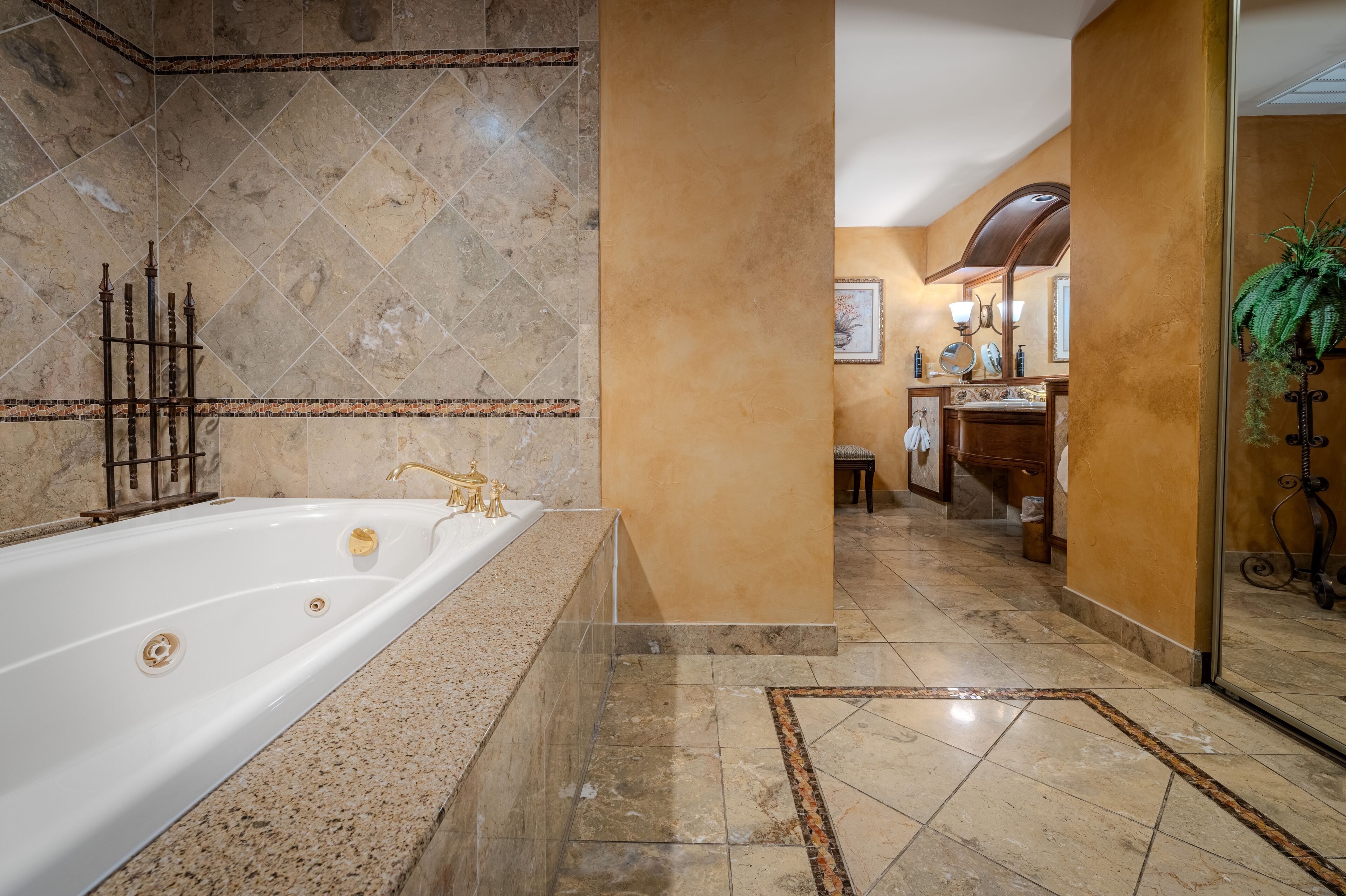 A luxurious bathroom with a large bathtub, marble tiles, and a modern vanity.