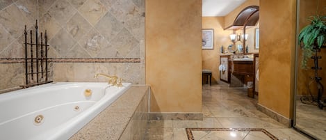 A luxurious bathroom with a large bathtub, marble tiles, and a modern vanity.