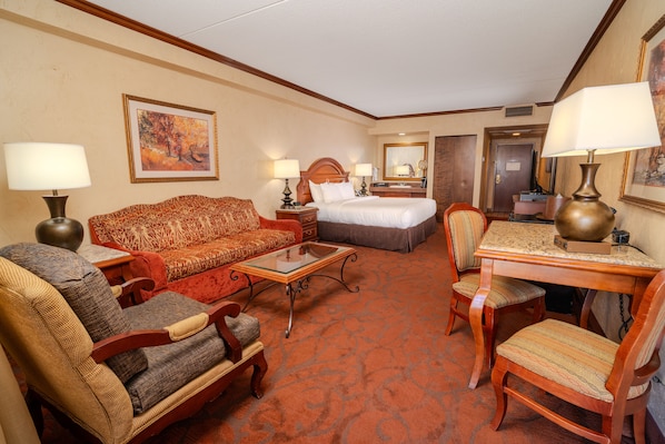 Una habitación de hotel con una cama, un sofá, un escritorio y dos sillas.