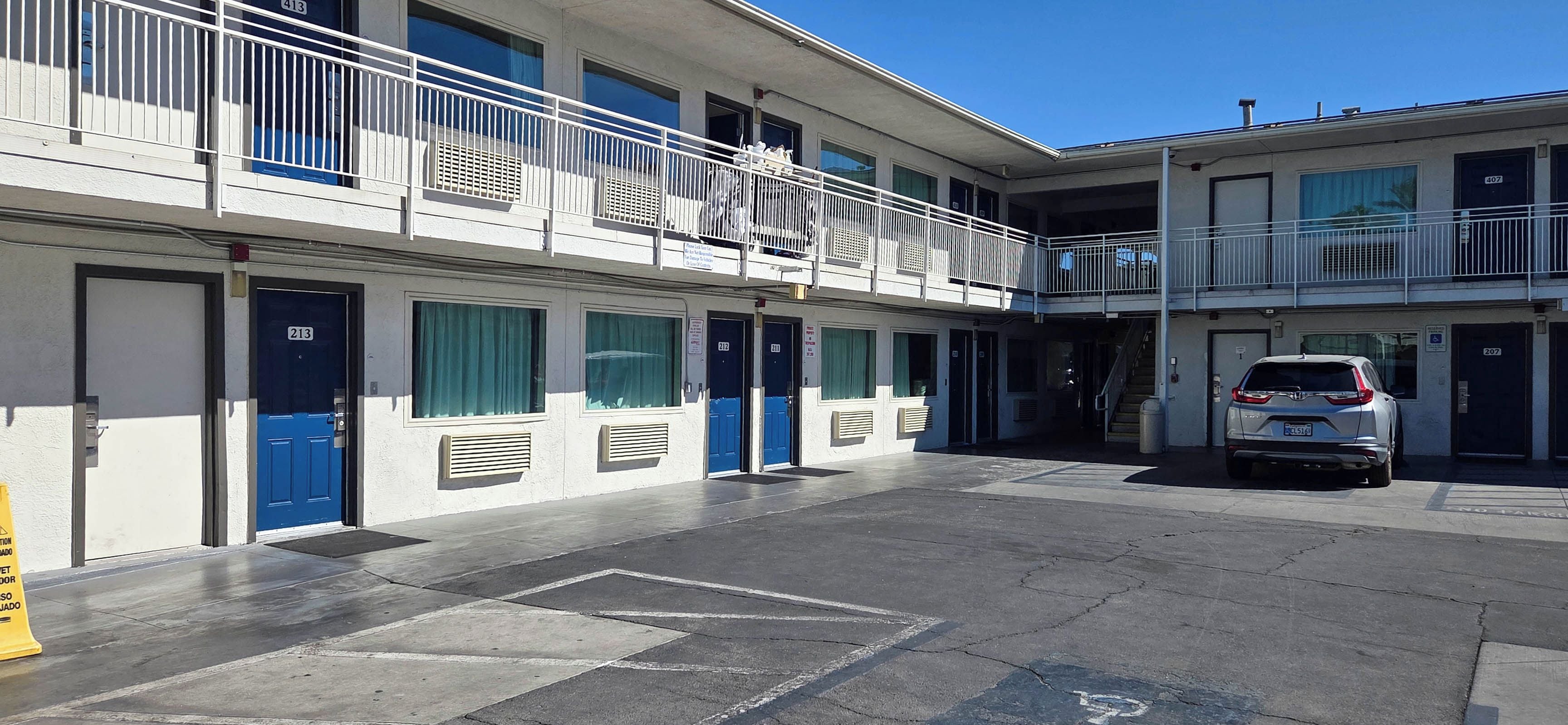 Un motel à plusieurs étages, doté de chambres individuelles, d’un parking et d’un escalier menant à l’étage supérieur.